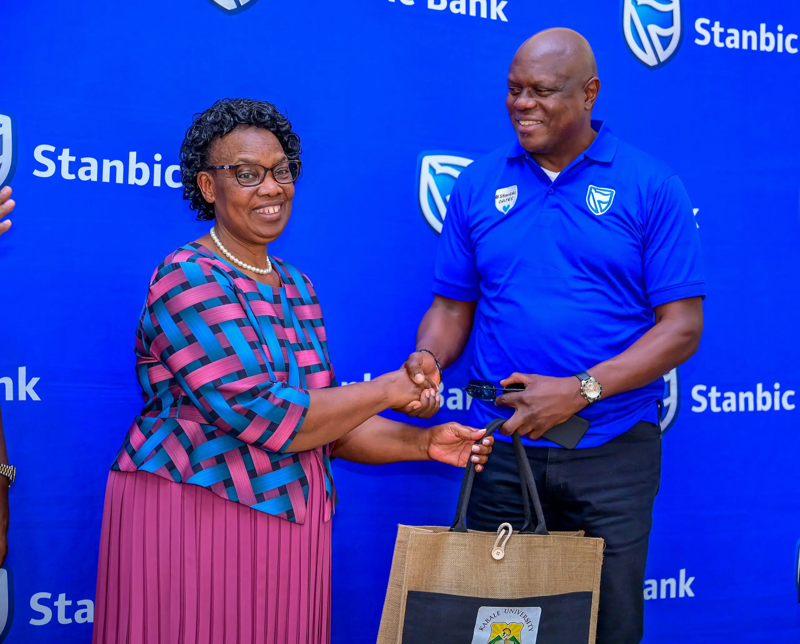 Kabale University Deputy Vice Chancellor Associate Professor Helen Musanabera Byamugisha handing over a gift to SUHL Chief Executive Mark Ocitti Ongom Kabale University Deputy Vice Chancellor Associate Professor Helen Musanabera Byamugisha handing over a gift to SUHL Chief Executive Mark Ocitti Ongom